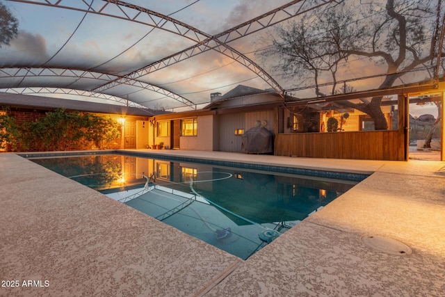 pool at dusk featuring a patio area and an outdoor pool