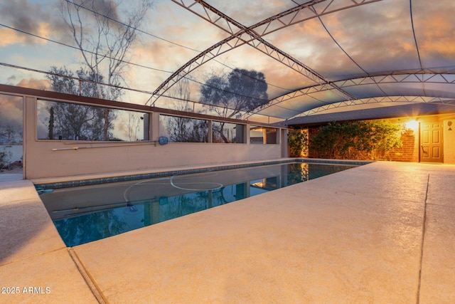 pool at dusk with a patio and an outdoor pool