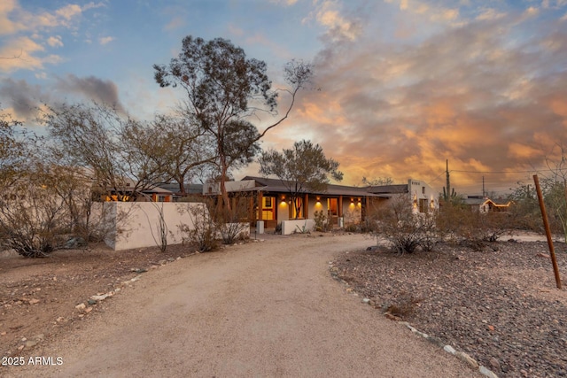 view of front of property featuring dirt driveway and fence