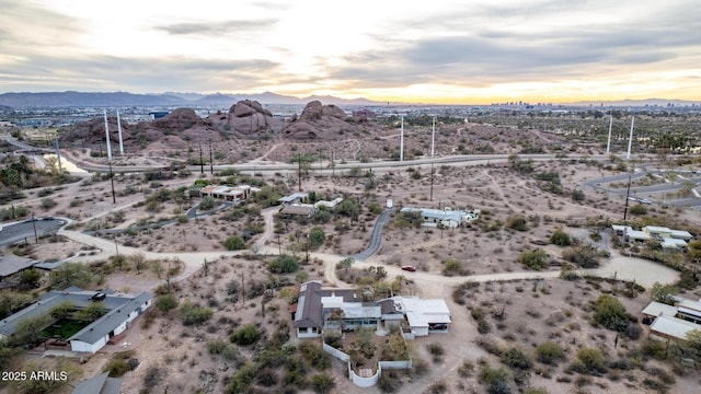 aerial view at dusk featuring a desert view and a mountain view