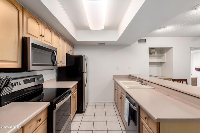 kitchen with sink, light tile patterned floors, stainless steel appliances, a raised ceiling, and light brown cabinets