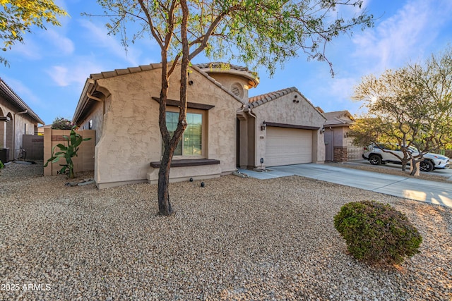 view of front of home with a tile roof, stucco siding, concrete driveway, fence, and a garage