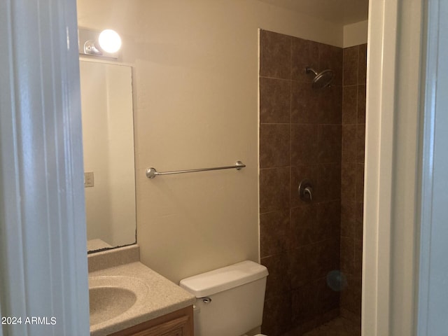 bathroom with vanity, a tile shower, and toilet