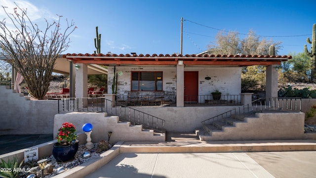 view of front of house with covered porch, a tiled roof, and stairs