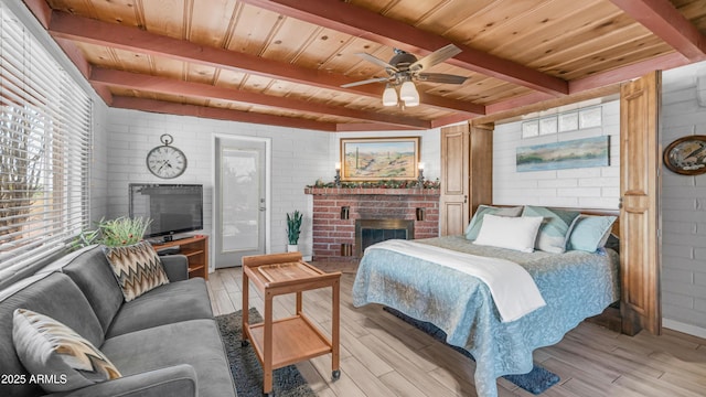 bedroom with a brick fireplace, beamed ceiling, wooden ceiling, and light wood-style flooring