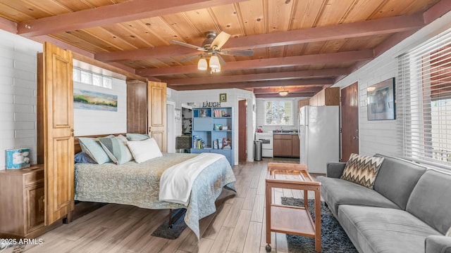 bedroom featuring light wood-style floors, beamed ceiling, freestanding refrigerator, and wooden ceiling