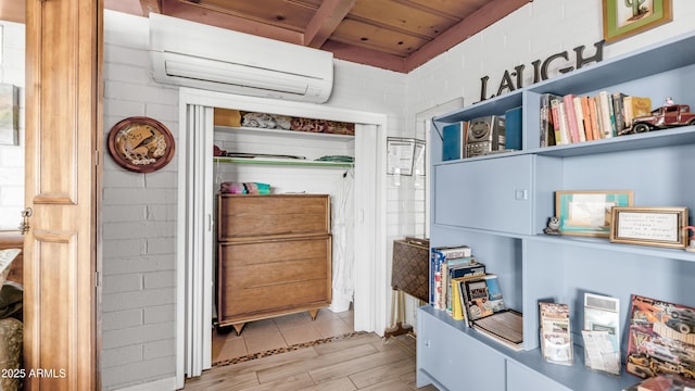 interior space featuring beam ceiling, a wall mounted AC, wooden ceiling, and wood finished floors