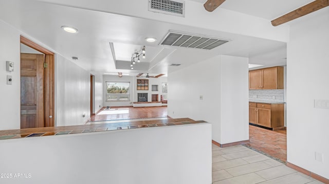 kitchen with visible vents, a raised ceiling, light tile patterned floors, and backsplash