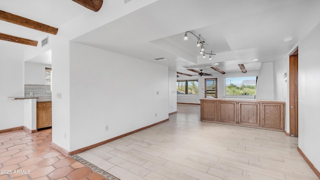 unfurnished living room featuring ceiling fan, visible vents, track lighting, baseboards, and beamed ceiling