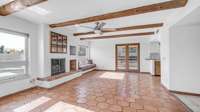 unfurnished living room featuring visible vents, a fireplace with raised hearth, beam ceiling, and a wealth of natural light