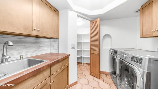 laundry area featuring cabinet space, light tile patterned flooring, washer and dryer, a sink, and visible vents