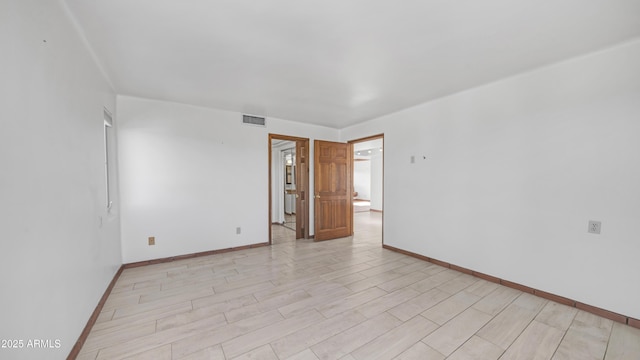 spare room featuring visible vents, baseboards, and light wood finished floors
