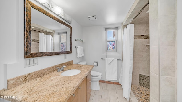 full bathroom with toilet, visible vents, a tile shower, and vanity