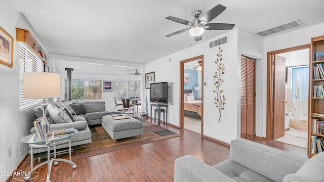 living area featuring baseboards, ceiling fan, wood finished floors, and visible vents