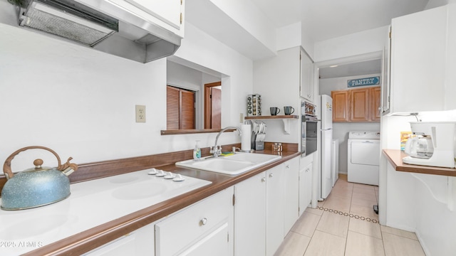 kitchen with white electric cooktop, a sink, white cabinets, light tile patterned flooring, and oven