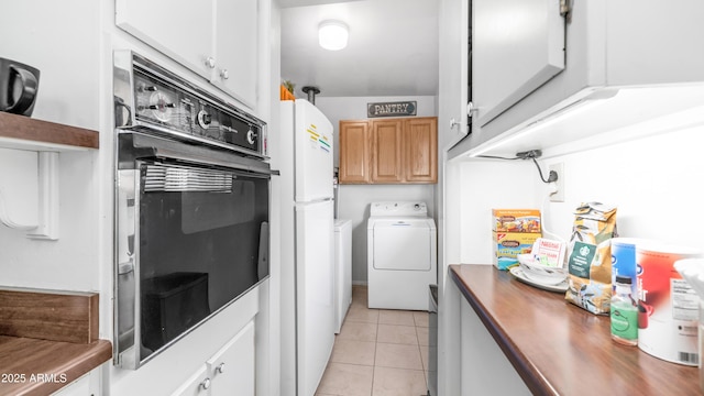 kitchen featuring freestanding refrigerator, washing machine and dryer, wooden counters, oven, and light tile patterned floors
