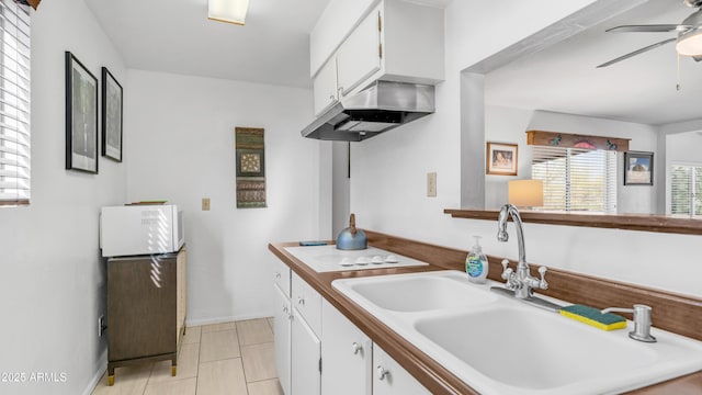 kitchen with a sink, white cabinetry, a ceiling fan, and under cabinet range hood