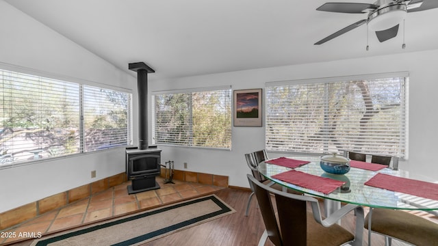 dining room with vaulted ceiling, a ceiling fan, and a wood stove