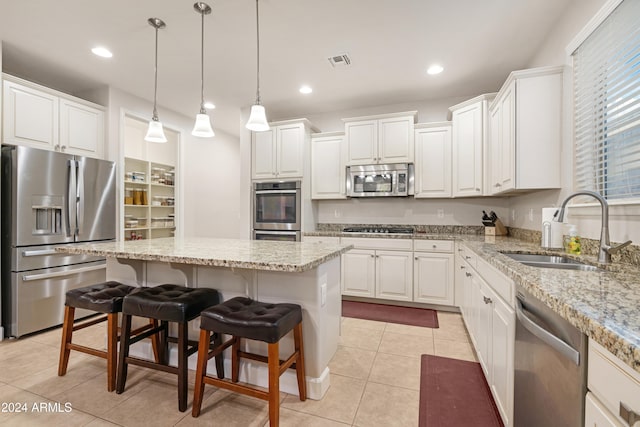 kitchen with sink, a center island, stainless steel appliances, white cabinets, and light tile patterned floors