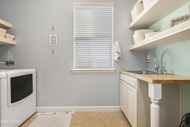 laundry room featuring washer / clothes dryer, a healthy amount of sunlight, sink, light tile patterned floors, and cabinets