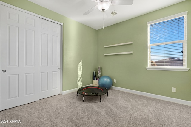 workout area featuring ceiling fan and light colored carpet