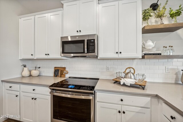 kitchen with backsplash, white cabinets, and stainless steel appliances