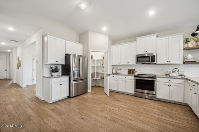 kitchen featuring decorative backsplash, white cabinetry, stainless steel appliances, and vaulted ceiling