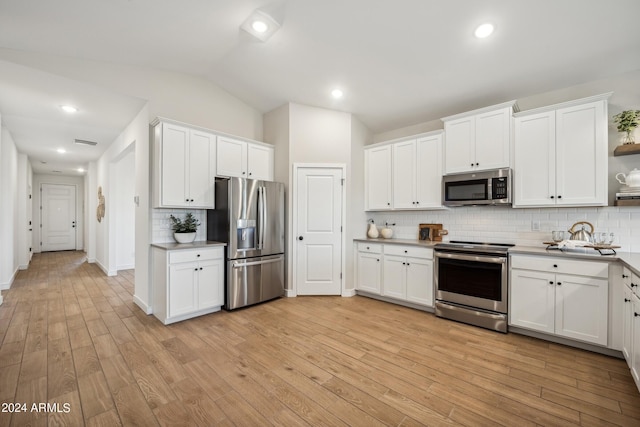 kitchen featuring vaulted ceiling, white cabinetry, appliances with stainless steel finishes, and tasteful backsplash