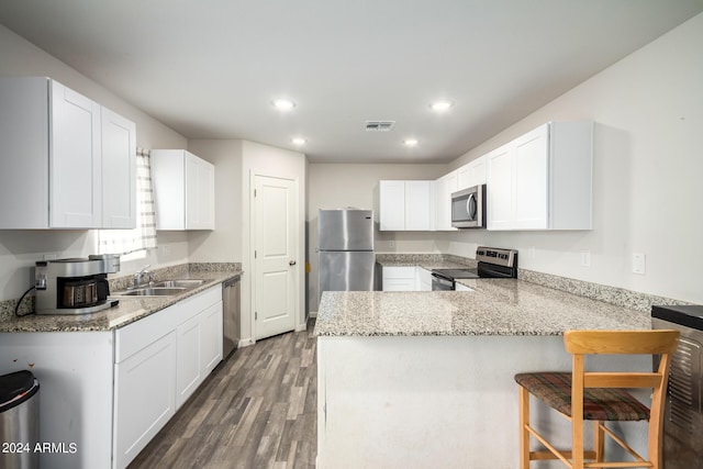 kitchen with light stone counters, visible vents, appliances with stainless steel finishes, a sink, and a peninsula