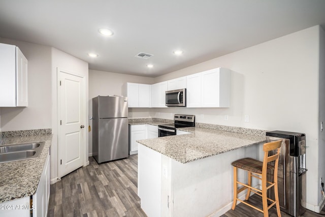 kitchen with dark wood finished floors, visible vents, appliances with stainless steel finishes, white cabinetry, and a peninsula