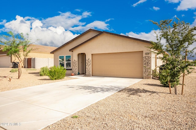 view of front of house featuring a garage, driveway, fence, and stucco siding