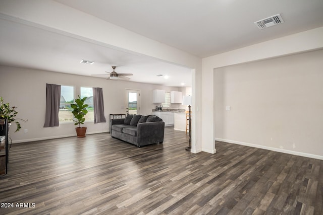 living area with baseboards, visible vents, and dark wood-type flooring