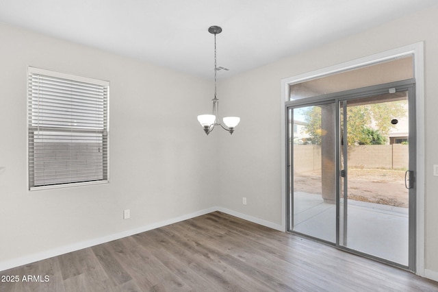 unfurnished dining area featuring hardwood / wood-style flooring and a notable chandelier