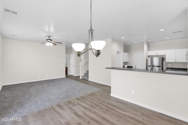 unfurnished living room featuring hardwood / wood-style flooring and ceiling fan with notable chandelier