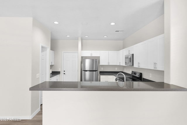 kitchen featuring white cabinetry, stainless steel appliances, kitchen peninsula, and sink