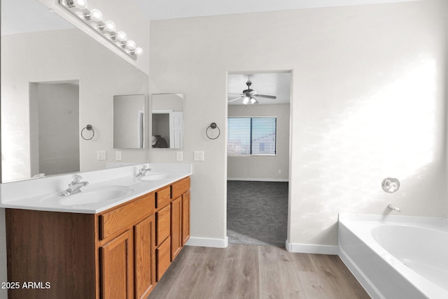 bathroom featuring hardwood / wood-style floors, vanity, a washtub, and ceiling fan