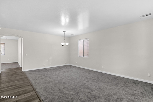 unfurnished room featuring an inviting chandelier and dark hardwood / wood-style floors