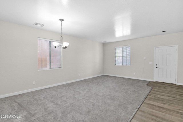 spare room with hardwood / wood-style flooring and a notable chandelier