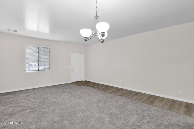 unfurnished room featuring a chandelier and carpet