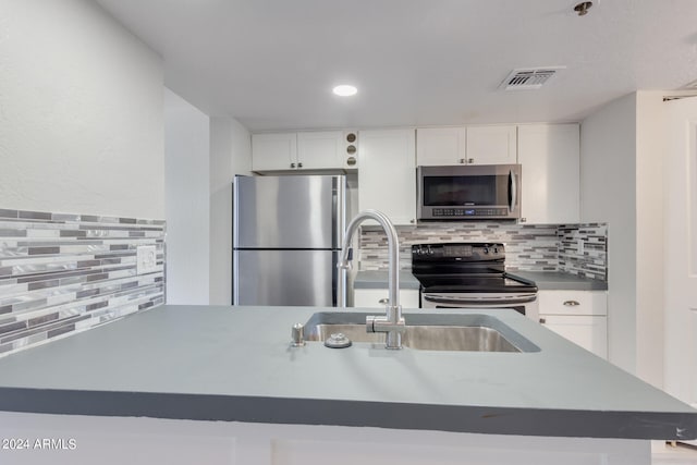 kitchen with tasteful backsplash, white cabinets, and appliances with stainless steel finishes