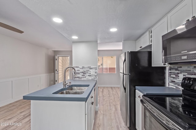 kitchen featuring light wood-type flooring, sink, white cabinetry, black range with electric cooktop, and backsplash