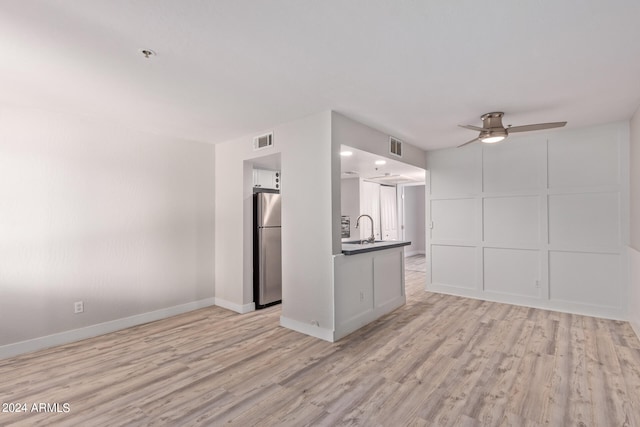 unfurnished living room featuring ceiling fan, light hardwood / wood-style flooring, and sink