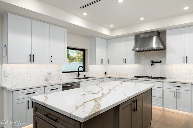 kitchen with white cabinetry, sink, and wall chimney range hood