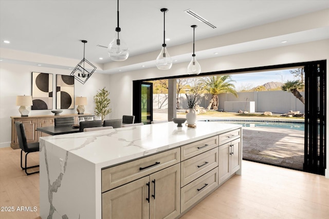 5919 N 45th St, Phoenix, AZ 85018 - kitchen featuring recessed lighting, light wood-style floors, a kitchen island, light stone countertops, and decorative light fixtures