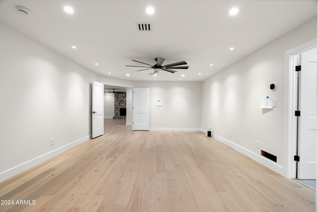 empty room featuring a barn door, ceiling fan, and light wood-type flooring