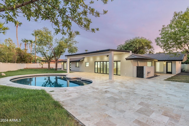 pool at dusk with a patio area