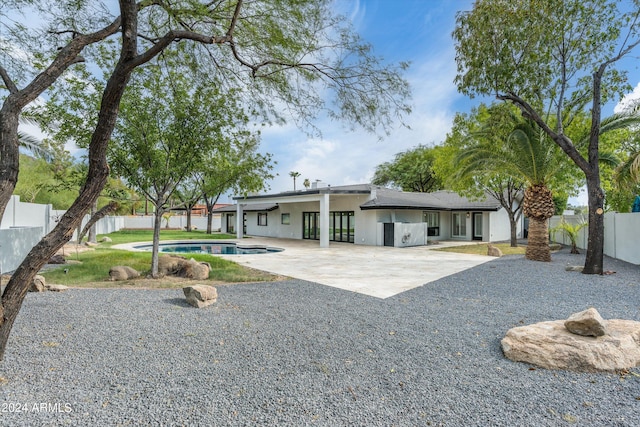 rear view of property featuring a fenced in pool and a patio