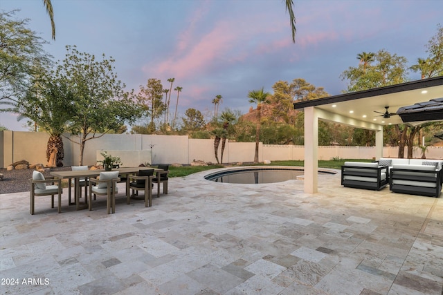 patio terrace at dusk with a fenced in pool, outdoor lounge area, and ceiling fan