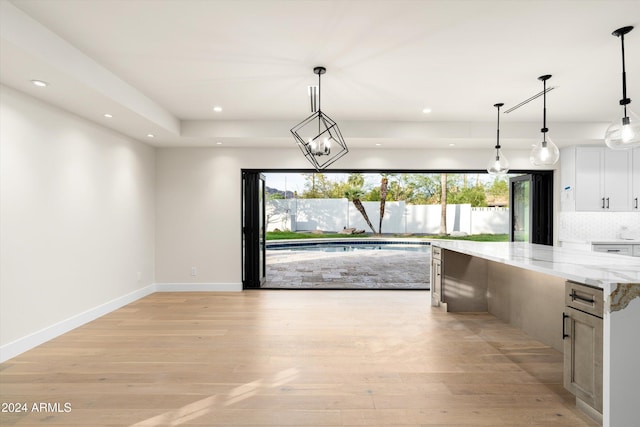 kitchen featuring white cabinetry, decorative light fixtures, light stone countertops, and light hardwood / wood-style floors