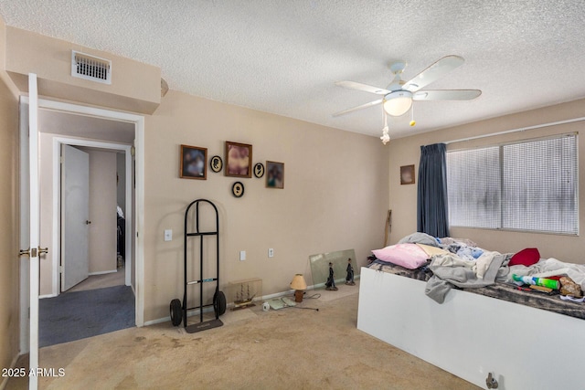 bedroom with ceiling fan, light carpet, and a textured ceiling